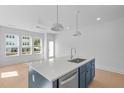 A modern kitchen with a blue island, stainless steel appliances and light hardwood floors at 5049 Lundy Dr # 101, Raleigh, NC 27606