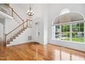 Bright foyer features hardwood floors, a staircase, a high ceiling, and a large window at 802 Windermere Lake Ct, Apex, NC 27502