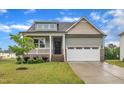 Inviting home featuring a two-car garage, landscaped front yard, and covered porch with white railing at 9 Little Sunshine Brk, Smithfield, NC 27577