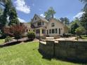 Beautiful backyard featuring a stone patio with retaining wall, lush lawn, and mature trees at 90021 Hoey, Chapel Hill, NC 27517