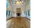 Well-lit living room featuring a stone fireplace, custom built-ins, hardwood floors, and large windows at 90021 Hoey, Chapel Hill, NC 27517