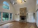Bright living room featuring a stone fireplace, custom built-ins, hardwood floors, and large windows at 90021 Hoey, Chapel Hill, NC 27517