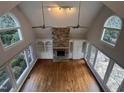 Spacious living room with vaulted ceiling, stone fireplace, hardwood floors, and walls of windows at 90021 Hoey, Chapel Hill, NC 27517