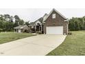 Brick two-story home featuring an attached garage and a long concrete driveway at 9123 Thomas Rd, Rocky Mount, NC 27803