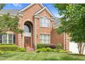Elegant brick home featuring a grand entryway with arched windows and manicured landscaping at 9639 Clubvalley Way, Raleigh, NC 27617