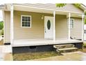 Close up of the front porch, featuring a decorative glass front door, white columns and a concrete foundation at 1309 Jackson St, Burlington, NC 27217