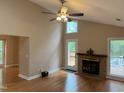 Bright living room featuring hardwood floors, a ceiling fan, and a brick fireplace leading to an outdoor deck at 200 W Woodcroft Pkwy # 52A, Durham, NC 27713