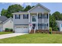 Charming two-story home with a covered front porch, an American flag, a two-car garage, and a well-manicured lawn at 2003 Pilot Mountain Ct, Apex, NC 27502