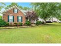 Attractive brick home featuring a green lawn, mature trees, and well-maintained landscaping at 2030 Prairie Ridge Ct, Fuquay Varina, NC 27526