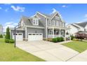 Spacious driveway leading to a gray two-story home with a two-car garage and basketball hoop for recreational activities at 320 Chickasaw Plum Dr, Holly Springs, NC 27540