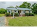Charming home features a bright blue metal roof, manicured landscaping, and paved front walkway at 403 Rolling Rd, Haw River, NC 27258