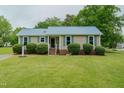 Charming home features a bright blue metal roof, manicured landscaping, and covered front entry at 403 Rolling Rd, Haw River, NC 27258
