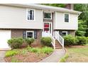 Close-up of front entrance with red door, white trim, brick, and manicured landscaping at 5001 Simpson Dr, Sanford, NC 27330