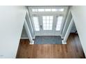 Bright foyer featuring hardwood floors, an overhead transom window, and decorative pillars at 5016 Trembath Ln, Cary, NC 27519
