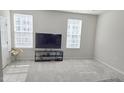 Bright living room with plush carpeting, modern TV, and plenty of natural light at 904 Romeria Dr, Durham, NC 27713