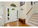Inviting entryway with hardwood floors, decorative wreath, and staircase leading upstairs at 1025 Kingsway Dr, Apex, NC 27502