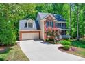 Spacious driveway leading to a brick home with attached garage and manicured landscaping at 105 Wittenham Dr, Cary, NC 27519