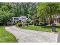 Home exterior showcasing lush landscaping, mature trees, and a long driveway leading to the house at 1120 Berwyn Way, Raleigh, NC 27615