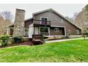 Two-story home displaying a stone chimney, balcony, and well-manicured lawn at 13 Crosswinds Estates Dr, Pittsboro, NC 27312