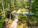 Aerial view of a property featuring a pool, a long driveway, mature trees, and a large yard at 1608 New Hill Olive Chapel Rd, Apex, NC 27502