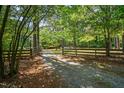 Long gravel driveway leads to a wooded property with a split-rail fence at 1608 New Hill Olive Chapel Rd, Apex, NC 27502