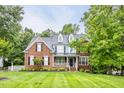 Charming brick two-story home featuring a well-manicured lawn, dormers, and a welcoming front porch at 244 Mantle Dr, Clayton, NC 27527