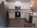 Bright kitchen featuring white cabinets, granite countertops, stainless steel appliances, and wood flooring at 31 Kevior Ave, Four Oaks, NC 27524