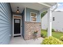 Inviting front porch with brick accents, an exterior light, and a view of the well-maintained lawn at 320 Everly Mist Way, Wake Forest, NC 27587