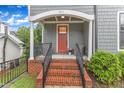 Charming front porch with brick steps, white columns, and a welcoming orange door at 511 Hamilton Cottage Way, Raleigh, NC 27605