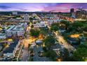 Twilight aerial view of a vibrant city skyline with a mix of commercial buildings and residential homes at 710 W North St # 103, Raleigh, NC 27603
