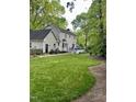 Expansive backyard featuring lush green lawn, mature trees, a patio area, and a charming deck with railing at 7517 Chippenham Ct, Raleigh, NC 27613