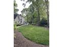 Beautiful backyard with lush green lawn, mature trees, and a patio with a deck that enhances the outdoor living space at 7517 Chippenham Ct, Raleigh, NC 27613