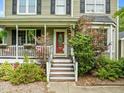 Close-up of the front steps and porch, featuring a bright red door and trimmed landscaping at 7621 Troy Stone Dr, Fuquay Varina, NC 27526