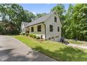 View of the home featuring a white exterior, dark trim, attached garage, and lush landscaping at 10817 Brass Kettle Rd, Raleigh, NC 27614