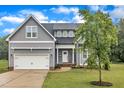 Beautiful gray home with a manicured lawn, attached garage, and inviting front porch at 1109 Agio Ct, Zebulon, NC 27597