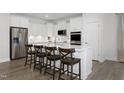 Modern kitchen features a center island with seating, stainless steel appliances, and white cabinets at 135 Harmony Ranch Lane, Franklinton, NC 27525