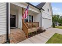 Welcoming front porch with brick steps, wooden railings, and American flag, leading to a cozy entrance and attached garage at 297 Sexton Ln, Wendell, NC 27591