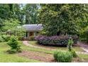 Inviting single story home with a well-manicured lawn, mature trees, and a winding brick path to the front entrance at 3125 Stanford Dr, Durham, NC 27707