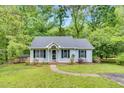 Charming single-story home featuring a well-manicured lawn, walkway, and inviting front porch, framed by lush trees at 324 Waterside Dr, Sanford, NC 27330