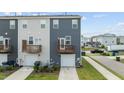 Exterior view of townhome featuring a small deck or balcony, garage, and well-maintained lawn at 6352 Perry Creek Rd, Raleigh, NC 27616