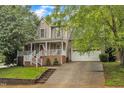 Charming two-story home with a welcoming front porch, brick accents, attached garage, and well-manicured landscaping at 6828 Edwell Ct, Raleigh, NC 27617