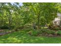 Lush backyard featuring green grass, mature trees, and lush landscaping with a wrought iron fence at 800 E Forest Hills Blvd, Durham, NC 27707