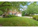 Charming brick home with green lawn, mature trees, and attached two car garage at 825 Federal House Ave, Wake Forest, NC 27587