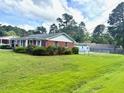 Quaint brick home showcasing a spacious yard and additional outbuilding structures at 100 E Dale Dr, Oxford, NC 27565