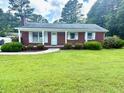 Well-kept red brick home with a lush green lawn and manicured shrubbery at 100 E Dale Dr, Oxford, NC 27565