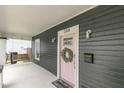 Close up of a front porch featuring a swing, pink door with greenery wreath and house number at 106 E Delafield Ave, Durham, NC 27704