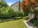 Green front yard featuring a stone retaining wall, mature tree, and water feature near the home at 107 Ashwick Ct, Cary, NC 27513