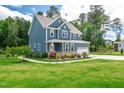 Beautifully landscaped property with a blue home, green lawn and trees at 108 Wilson Farm Ln, Clayton, NC 27527