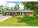Charming single-story home featuring a red door, brick accents, manicured lawn and a convenient covered carport at 1209 Maple Ave, Apex, NC 27502