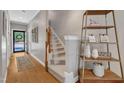 Inviting foyer with hardwood floors, a carpeted staircase, and decorative shelving unit, offering a warm welcome at 137 Lanigan Pl, Cary, NC 27513